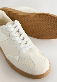 Hvide sneakers lavet af læder med en glat tekstur, der har et perforeret design, flade hvide snørebånd og en slidstærk gummisål.