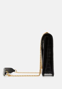 Czarna torba z lakierowanej skóry z teksturą krokodyla, wydłużony kształt i złoty łańcuszek na ramię. Posiada jednolity czarny tył.