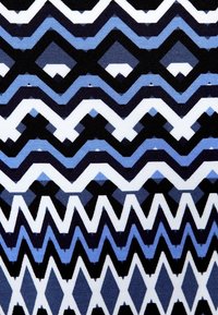 Wzorzysta tkanina z wyraźnymi kształtami zygzaków i diamentów w odcieniach granatowego, jasnoniebieskiego, czarnego i białego. Gładka faktura.