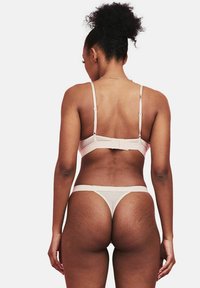 Lichtroze lingerie set met een bh met dunne banden en een string, gemaakt van zacht materiaal met verstelbare banden en een minimalistisch ontwerp.