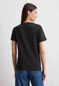 Zwarte t-shirt met korte mouwen en een schoon ontwerp, met een subtiele logoprint op de bovenrug. Gemaakt van soepel, lichtgewicht katoen.