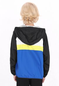 Jachetă de vânt colorată, cu panouri negre, albe, galbene și albastre, dotată cu glugă și manșete elastice. Material ușor.