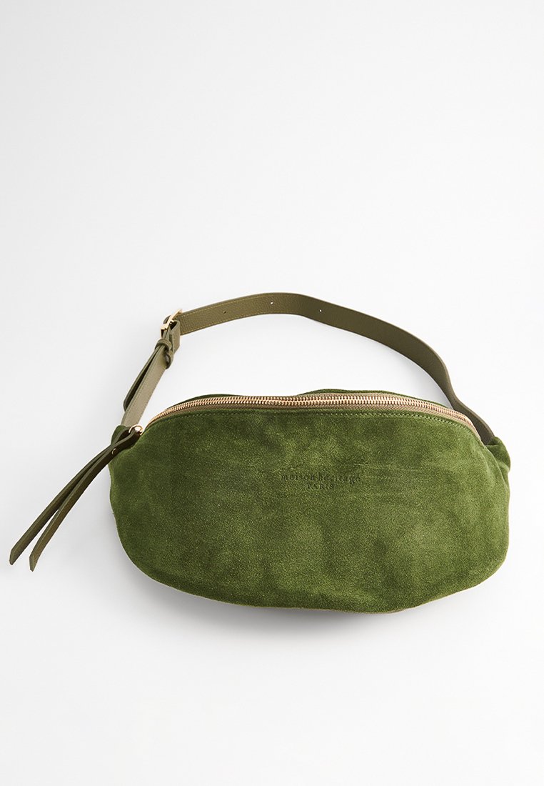 Olivengrüne Wildledertasche mit runder Form, Reißverschluss und verstellbarem Trageriemen. Verfügt über einen Quastenakzent am Riemen.