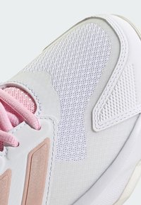 Sport shoe with a white synthetic upper, pink laces, and textured mesh panels. Features light-colored accents and a rubber sole.