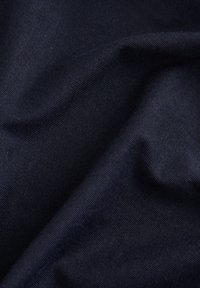 Námořnická modrá látka s měkkým, texturovaným povrchem, vykazující jemné protažení a detailní tkané vzory.