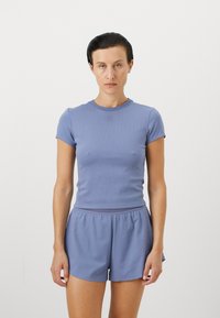 T-shirt blu in cotone aderente con maniche corte e tessuto a costine, abbinato a pantaloni corti blu coordinati con vita elastica.