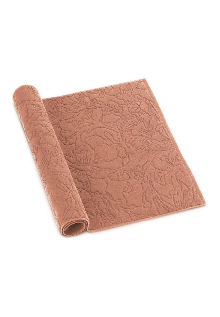 Tappeto textured di colore terracotta con un motivo floreale, parzialmente arrotolato, caratterizzato da una superficie morbida e soffice e un bordo resistente per una maggiore stabilità.