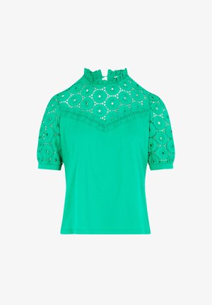 Vihreä lyhythihainen paita, jossa on voimakkaasti röyhelöity korkea kaulus. Hihnoissa ja yläosassa on pitsimäinen kangas, jossa on ympyrämuotoisia aukkoja.