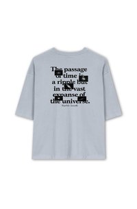 Light blue oversized t-shirt with short sleeves featuring black text, stating a quote about time, and a logo at the bottom.