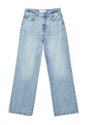 Lyseblå jeans med høj talje iført af en person, set bagfra, med vide ben og to baglommer. Sorte og marineblå armbånd på højre håndled.