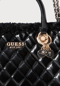 Borsa a tracolla nera trapuntata realizzata in materiale sintetico lucido, con hardware dorato e una texture simile alla pelliccia nella parte superiore. Decorata con pendenti del logo.
