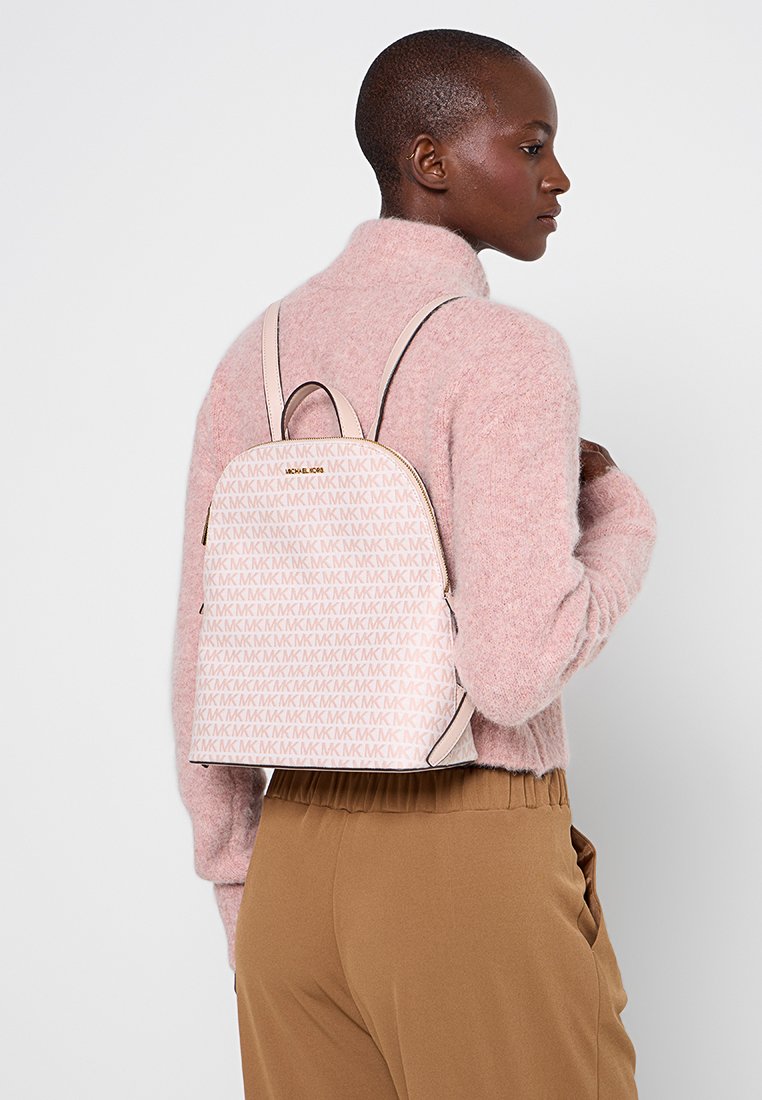 Roze leren rugzak met herhalend MK-logo patroon, afgeronde vorm en rits-sluiting. Bevat verstelbare schouderbanden en een gladde textuur.