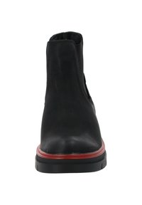 Botín negro hasta el tobillo con un upper de cuero liso, paneles laterales elásticos, acento en suela de goma roja y punta redondeada. Suela delgada texturizada.