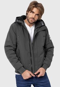 Gray padded jacket with a hood, featuring a zip closure, snap buttons, side pockets, and textured collar lining.