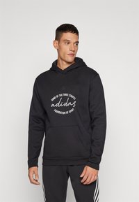 Felpa nera con tasca a marsupio, caratterizzata da un logo e testo stampati in bianco. Tessuto morbido, cappuccio con cordino e polsini a coste.