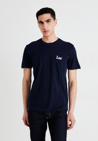 Mørkeblå bomulls t-skjorte med korte ermer, som har en liten hvit "Lee" logo på venstre brystområde. Glatt tekstur og klassisk passform.