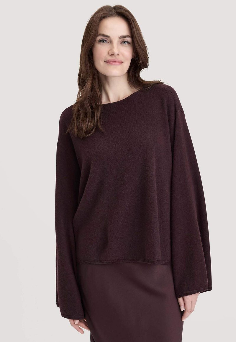 Burgunderfarbener, übergroßer Pullover mit langen Ärmeln und weitem Ausschnitt, aus weichem Stoff gefertigt, mit einem gerippten Saum am unteren Ende.
