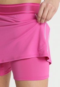 Roze sportshorts met een brede tailleband met dubbele strepen, gelaagd ontwerp en een witte logoaccent aan de zijkant. Zacht, rekbaar materiaal.