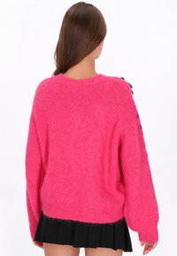 Pulover roz supradimensionat, din material pufos, cu guler rotund și manșete ribbate. Spate simplu, fără detalii sau embellishments suplimentare.