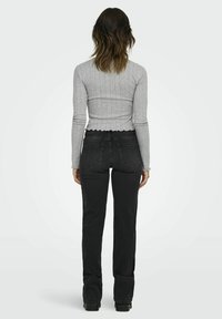 Grijze geribde longsleeve top met een golvende zoom; gecombineerd met zwarte high-waisted Jeans met twee achterzakken en een slim fit.