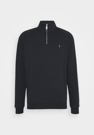 Schwarzer Sweatshirt mit einem Reißverschluss am hohen Kragen, gerippten Bündchen und Saum. Verziert mit einem kleinen goldenen Logo auf der Brust. Weiche, glatte Textur.