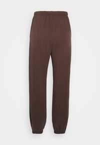 Bruna sweatpants med elastisk midja och muddar. Tillverkade av ett mjukt, slätt material med en avslappnad passform och utan synliga fickor.