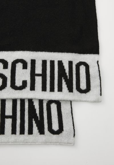 Svart og grå strikket skjerf med en fremtredende svart "MOSCHINO"-logo i fet skrift langs den nedre kanten. Myk tekstur og rektangulær form.