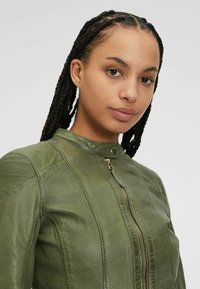 Grüne Lederjacke mit taillierter Passform, gerippten Schulterdetails und Stehkragen. Verfügt über einen zentralen Reißverschluss und goldene Hardware-Akzente.