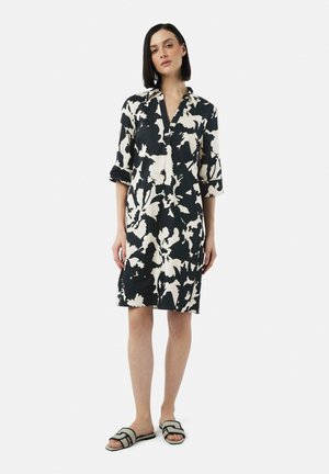Black and white floral dress with a collared neckline and three-quarter sleeves, featuring a loose fit and soft fabric. Worn with slide sandals.