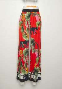 Pantalon large multicolore en tissu rouge vif avec imprimés botaniques et animaliers, doté d'une ceinture élastique noire.