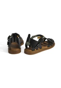 Schwarze Ledersandalen mit offenem Rücken, mehreren Riemen, brauner strukturierten Sohle und dekorativen Nieten und Akzenten.