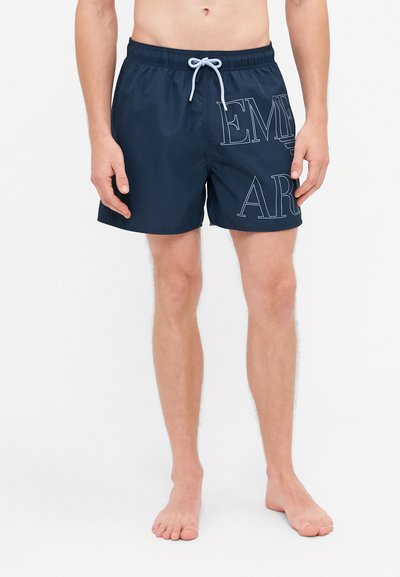 Pantaloni da nuoto blu navy in materiale leggero con elastico in vita, cordino e grande grafica ricamata "EMPIRE" sul lato.