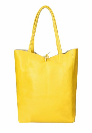 Żółta skórzana torba tote o gładkiej fakturze, z dwoma wydłużonymi uchwytami i otwartą górą zabezpieczoną sznurkiem. Minimalistyczny design.