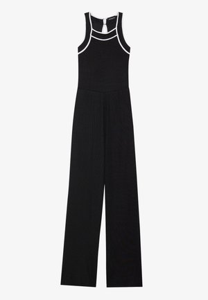 Tuta nera con gambe larghe, texture a coste e dettagli bianchi. Presenta un collo alto e una chiusura a fessura sul retro.