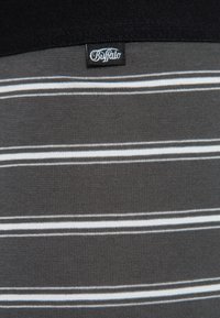 Gestreiftes T-Shirt aus schwarzem und grauem Stoff mit horizontalen weißen Streifen, weicher Textur und einem Logosticker am Kragen.