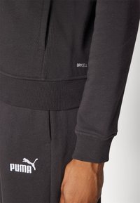 Juodas sportinis megztinis su suraizgytomis rankogaliais ir apvadu. Savyje turi "DRYCELL" prekės ženklą ir baltą "PUMA" logotipą priekyje. Minkšta tekstūra.