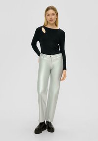 Zwarte geribbelde lange mouw top met een schouder uitsnijding, gecombineerd met glimmende zilveren wijde broek en zwarte platformlaarzen. Eenvoudig ontwerp en kleuren.