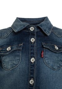 Džínová košile s tmavě modrým praním, klasickým límečkem, šesti knoflíky, dvěma předními kapsami a červeným logem na levé straně.