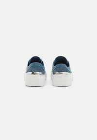 Blå canvas slip-on sneakers med en teksturert overflate, hvit gummisåle og metalliske detaljer ved hælen.