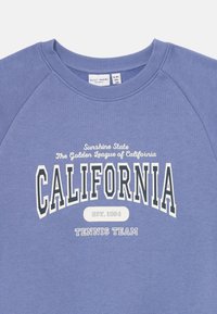 Sudadera crewneck azul con "Equipo de Tenis de California", "Estado del Sol" y "La Liga Dorada de California" impresos en texto blanco y negro.