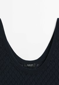 Haut sans manches en tricot bleu marine avec un motif en losange et un col arrondi, avec une étiquette Massimo Dutti à l'intérieur du col.
