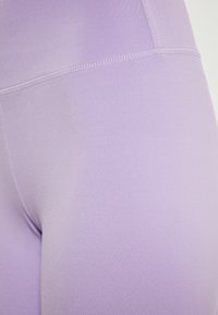 Sima, rugalmas anyagból készült lila leggings, magas derékkal és síkvarrásokkal, matt felülettel és látható minták nélkül.
