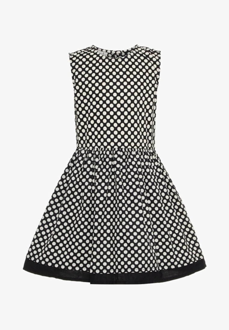Robe noire sans manches à pois blancs, taille ajustée et jupe évasée avec bordure noire à l'ourlet.