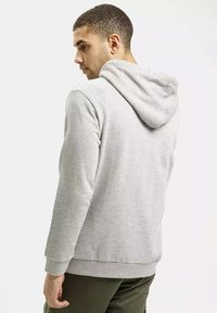 Szara bluza z kapturem wykonana z materiału bawełnianego, z regulowanym kapturem, ściągaczami przy rękawach oraz kieszenią kangurką. Gładka faktura i dopasowany krój.