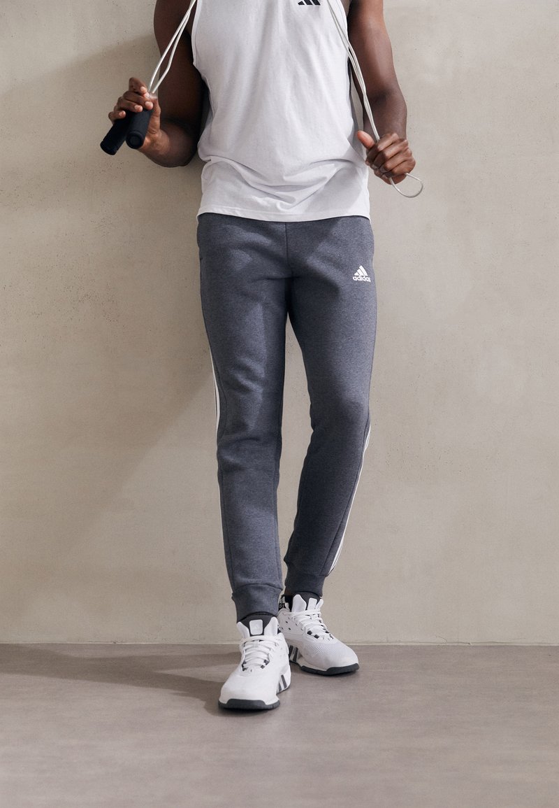 adidas Sportswear - ESSENTIALS TAPERED CUFF 3 STRIPES PANTS - Tracksuit bottoms - dark grey heather, Enlarge