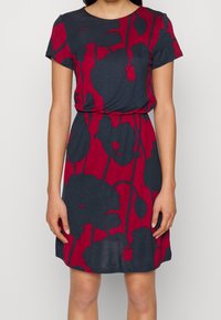 Robe à manches courtes en tissu doux, avec une base bleu marine ornée de grands motifs floraux rouges et une taille cintrée pour une silhouette flatteuse.