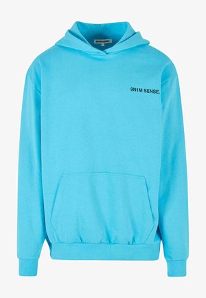 Gaiši zilas krāsas kapuce no mīksta auduma, ar priekšējo kabatu, ribinātiem piedurkņu galiem un mazu teksta logotipu uz krūškurvja.