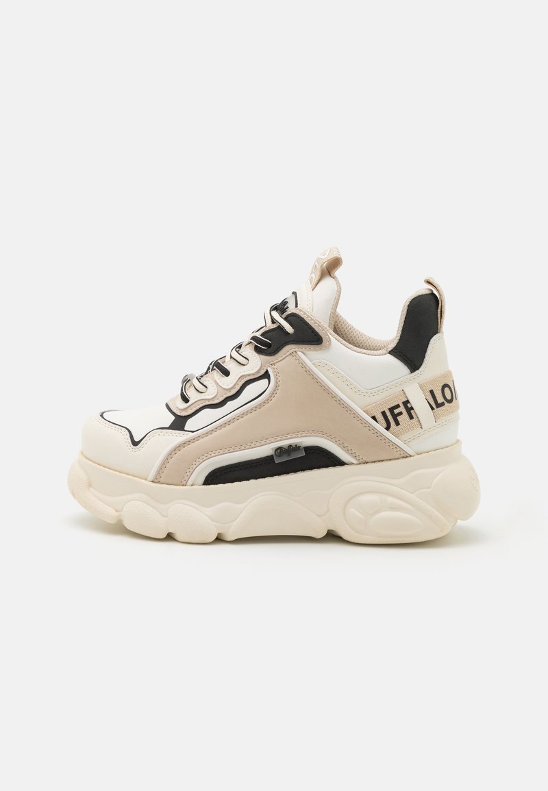 Sneakers med en kraftig krämfärgad sula, paneler i beige och vitt, svarta accenter och texturerade material. Har synliga snören och varumärkeslogotyp på hälen.