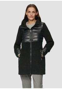 Manteau noir avec une partie supérieure rembourrée et brillante noire. Doté d'une capuche, d'une fermeture éclair et de poches latérales. Fabriqué en tissu doux avec des manches texturées.