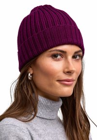 Beanie a coste viola con una vestibilità aderente e una finitura testurizzata, indossato con un dolcevita grigio chiaro, che mette in mostra un primo piano del design.